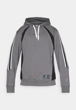 Grauer Kapuzenpullover mit schwarzen Akzenten, weißen Streifen an den Ärmeln, Kängurutasche und Logo-Patch am Saum. Aus weichem, strukturiertem Stoff hergestellt.