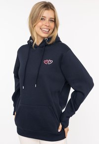 Granatowy hoodie z miękkiego materiału, z przednią kieszenią, sznurkiem do regulacji i różowym sercem na klatce piersiowej. Wygodny i casualowy krój.