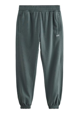 Pantaloni de trening gri închis cu talie și manșete elastice, buzunare laterale și mic logo alb „self.” pe coapsa dreaptă.