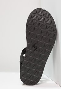 Black rubber sandal sole featuring a triangular tread pattern and a branded logo. Strap design visible along the edge.