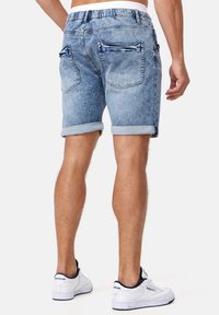 Lichtblauwe denimshorts met een opgerolde zoom, elastische tailleband en twee achterzakken. Draag ze met witte sneakers voor een casual look.