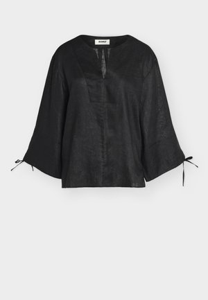 Blouse en lin noir avec manches larges trois-quarts, fente en V et liens aux poignets, présentée sur fond blanc.