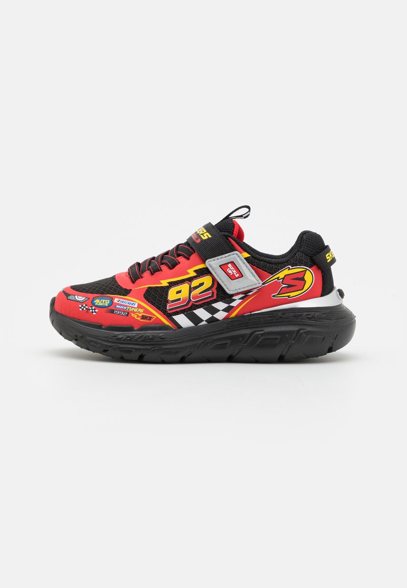 Zapatilla roja y negra con parte superior de malla, gráficos de rayos audaces, cuello acolchado y suela de goma gruesa. Presenta un diseño con cordones y una lengüeta.