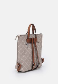 Sac à dos beige à motifs avec un design en diamants, poignées en cuir brun, et fermeture éclair. Comprend une poche arrière zippée.