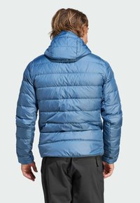 Chaqueta de plumas azul con patrón acolchado y capucha. Fabricada con un tejido liso y brillante, presenta puños elásticos y un diseño ajustado. Vista trasera mostrada.