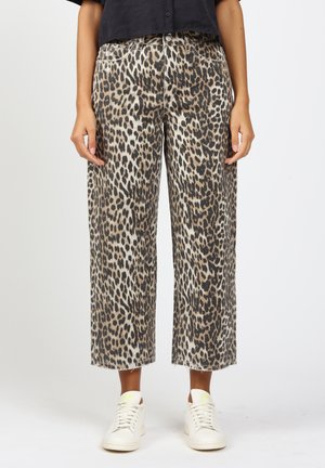 Leopardenmuster weit geschnittene Hosen mit fransigem Saum, aus leichtem Stoff. Kombiniert mit weißen Sneakern für einen lässigen Look.