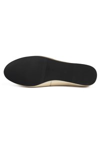 Suela de zapato beige con una forma suave, fondo de goma negra plana y sutiles surcos horizontales para tracción.