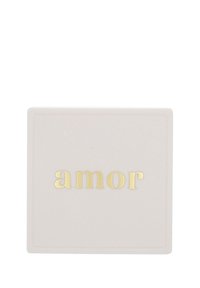 Vit fyrkantig keramisk platta med ordet "amor" präglat i gyllene bokstäver centrerat på en enfärgad bakgrund.