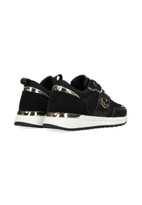 Paire de baskets basses noires et dorées avec semelles blanches, détails en mesh et cuir, et logo circulaire de la marque sur le côté.