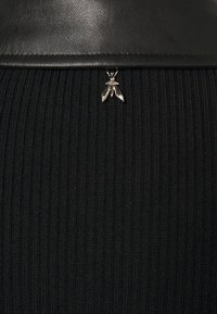 Tessuto nero a coste con una cintura liscia in pelle; presenta un piccolo dettaglio a forma di ape in argento attaccato nella parte anteriore.