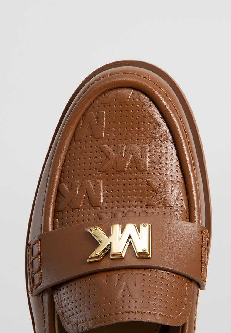 Braune Leder-Slipper mit einem strukturierten, geprägten Muster und einem goldenen Logoakzent auf einem breiten Riemen über dem Obermaterial.