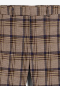 Pantalones de cuadros marrones con una tela texturizada con rayas azul marino y amarillas, frente plano, trabillas y dos bolsillos laterales.