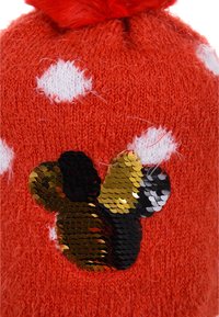 Rote gestrickte Mütze mit weißen Punkten, mit einem schwarzen und goldenen Pailletten-Schmetterlingsdesign und einem roten Pompon oben.