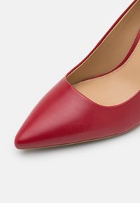 Chaussure plate pour femme en cuir rouge à bout pointu, avec doublure intérieure beige et finition lisse, sur fond blanc.