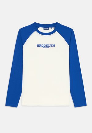 Langarm-Raglan-Shirt mit einem weißen Körper und königsblauen Ärmeln. Auf der Brust steht "BROOKLYN NEW YORK" in blauer Schrift. Aus Baumwollmaterial.