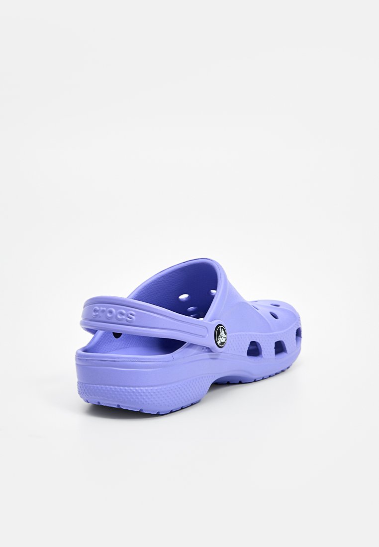 Zuecos morados de Crocs con agujeros de ventilación, tira trasera y suela texturizada. Fabricados en un material plástico ligero. Logo de la marca visible.