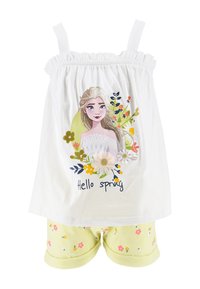 Weißes Tanktop mit elastischen Trägern, das ein Blumendesign und den Text "Hallo Frühling" zeigt. Kombiniert mit hellgelben Shorts mit Blumenmustern.