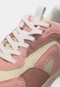 Růžová a béžová teniska s bílými tkaničkami, síťovinovým materiálem a semišovými překryvy, detail svršku a očínek.