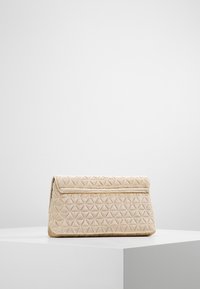 Beżowa pikowana kopertówka z geometrycznym wzorem, miękką teksturą i klapką na zakładkę. Kompaktowy design odpowiedni na formalne okazje.