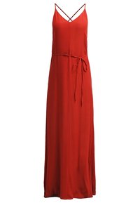 Robe longue rouge sans manches avec de fines bretelles croisées et une ceinture nouée à la taille.