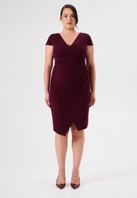 Burgunderfarbenes, tailliertes Kleid mit kurzen Ärmeln, V-Ausschnitt und Raffung an der Taille; knielang mit asymmetrischem Saum.