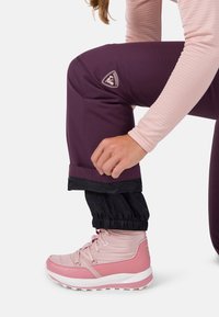 Water-resistant, purple pants with adjustable black cuffs paired with light pink waterproof boots, featuring laces and textured material.
