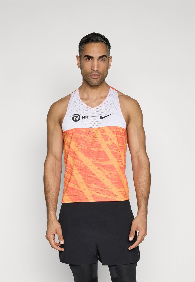 Orange und weißes sportliches Tanktop mit strukturiertem Muster, runder Ausschnitt und Branding auf der Brust. Schwarze Shorts mit glatter Oberfläche.