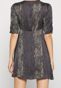 Short-sleeve dress in patterned dark green and black fabric, featuring a fitted waist and flowy skirt with subtle sheen and texture.