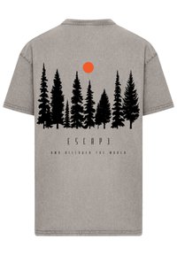Gray t-shirt featuring a black silhouette of pine trees, an orange sun, and the text "ESCAPE AND DISCOVER THE WORLD" in black below.