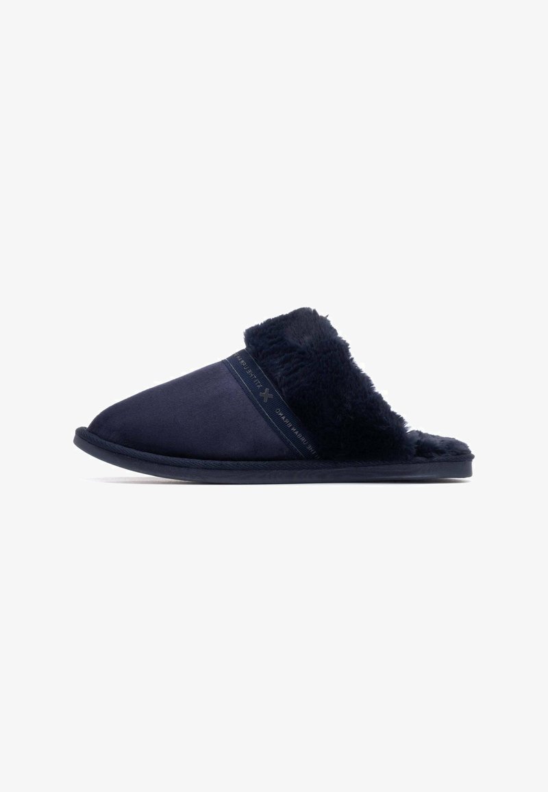 Pantuflas azul marino con un suave forro de piel sintética, parte superior de ante suave y suela acolchada. Diseño minimalista con acentos simples.
