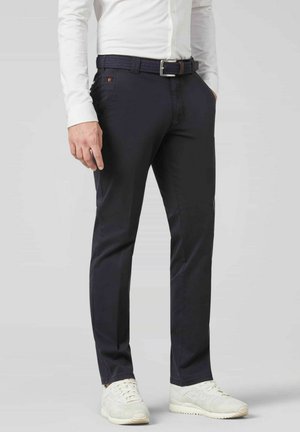 Navy-Hosen aus Baumwollmischung mit schmaler Passform, seitlichen Taschen und einem gewebten Gürtel. Kombiniert mit weißen Sneakern.