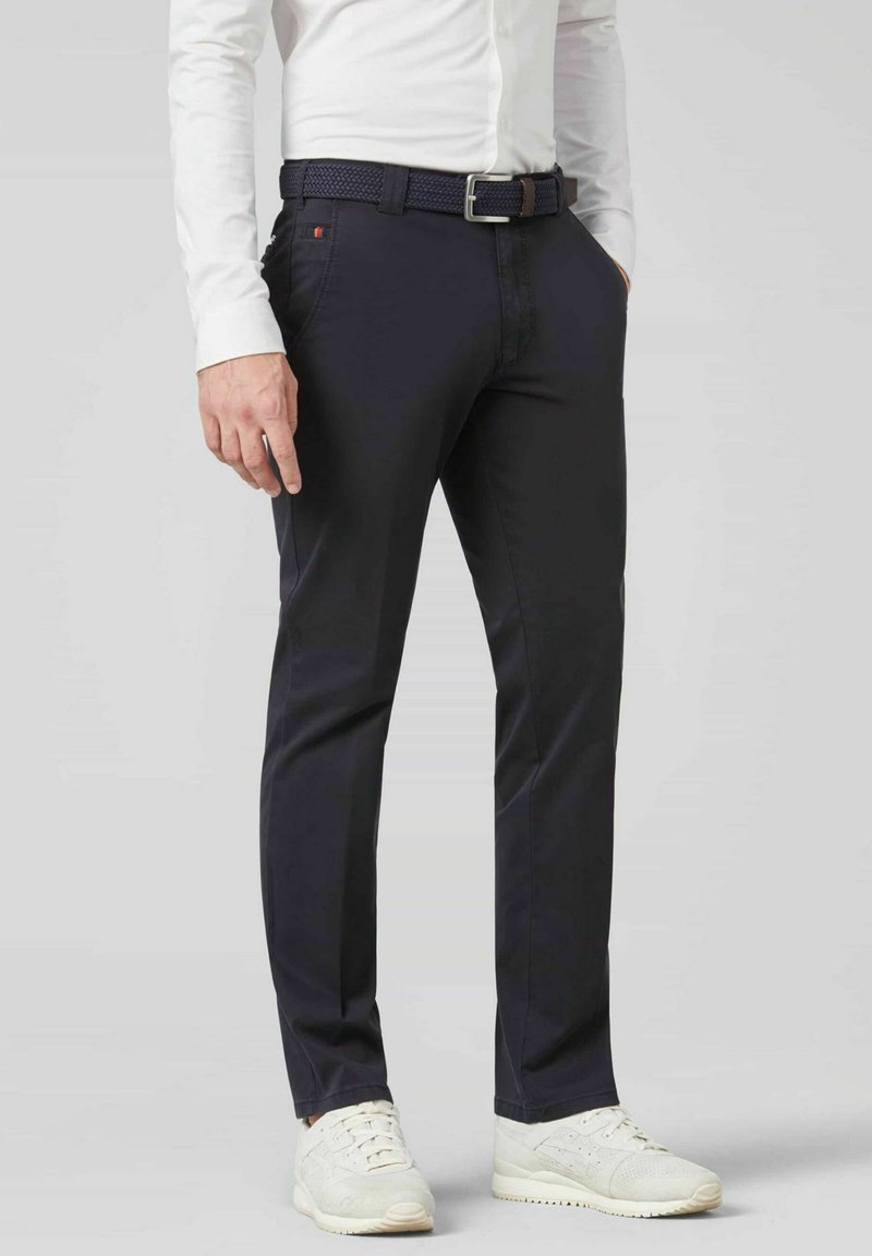 Pantalon navy en mélange de coton, présentant une coupe slim, des poches latérales et une ceinture tissée. Associé à des baskets blanches.