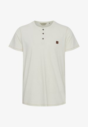 Svetlo bež henley majica s kratkimi rokavi, tremi gumbi na ovratniku in majhnim rjavim logotipom. Kontrastno šivanje daje poudarek oblikovanju.