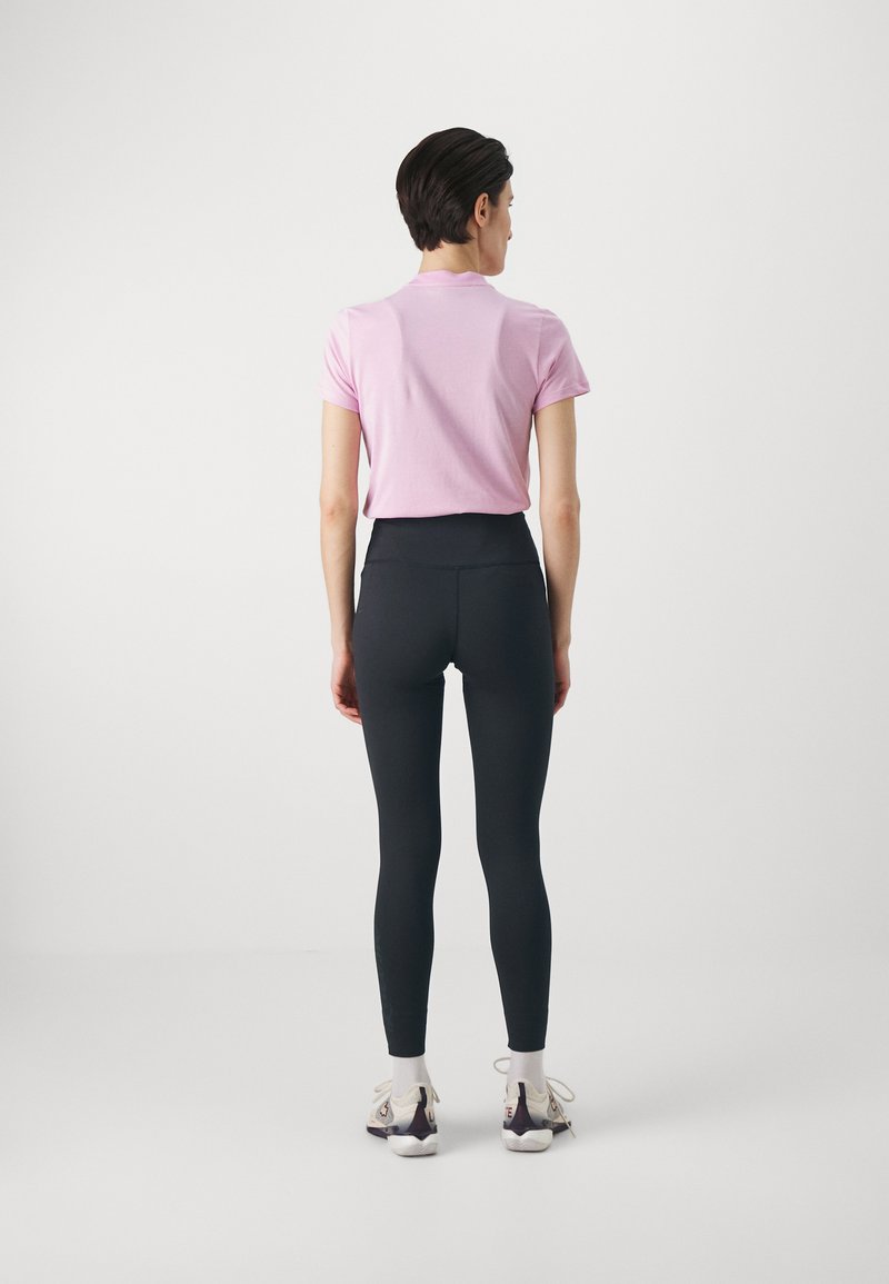 T-shirt rosa chiaro a maniche corte abbinato a leggings neri a vita alta. Tessuto morbido, design aderente, lunghezza alla caviglia senza motivi visibili.