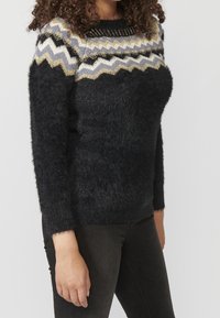 Schwarzer flauschiger Pullover mit einem Zickzackmuster in Grau, Weiß und Gold am Ausschnitt, mit langen Ärmeln und einer lockeren Passform.