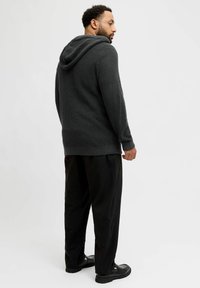 Haut à capuche en maille gris charbon avec une finition texturée, doté d'une capuche à cordon, de manches longues et de bords côtelés, associé à un pantalon noir.