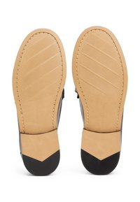 Semelles de chaussures en cuir noir avec une base en caoutchouc marron clair, présentant un design texturé et des accents noirs distincts au talon.