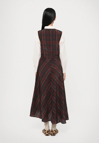 Abito lungo senza maniche con un motivo a quadri rosso e nero e strisce diagonali. Tessuto leggero, silhouette fluida e dettaglio in vita arricciato.