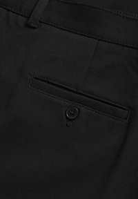 Pantalones de tela negra con un bolsillo trasero con un solo botón negro. La tela tiene una textura suave y un diseño ajustado.