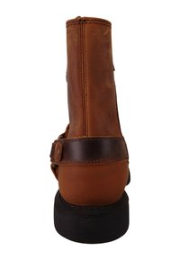 Botín de cuero marrón hasta el tobillo con punta redonda, cremallera trasera y detalle de correa en marrón oscuro. Presenta un tacón de goma negra apilada.