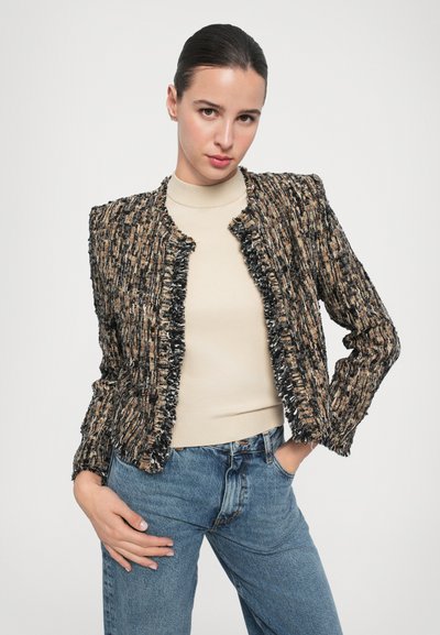Tweed jasje met een gestructureerd, multikleurig patroon. Het heeft een cropped ontwerp, rafelige randen en lange mouwen, gecombineerd met een beige top en jeans.