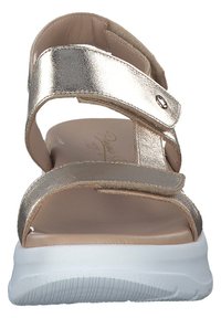 Guldmetallisk sandal med två justerbara remmar, vadderad innersula och vit gummisula. Har en texturerad, halkfri botten.