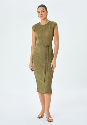 Vestito verde a maglia con maniche corte, forma aderente, vita con cintura e texture a coste. Accentuato con fili metallici. Lunghezza fino al polpaccio.