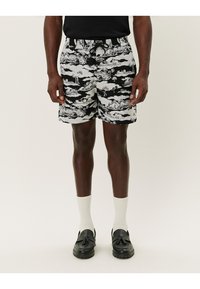Svart- och vitmönstrade shorts med ett molndesign, som har resårmidja och snöre. Matchas med vita strumpor och svarta loafer.