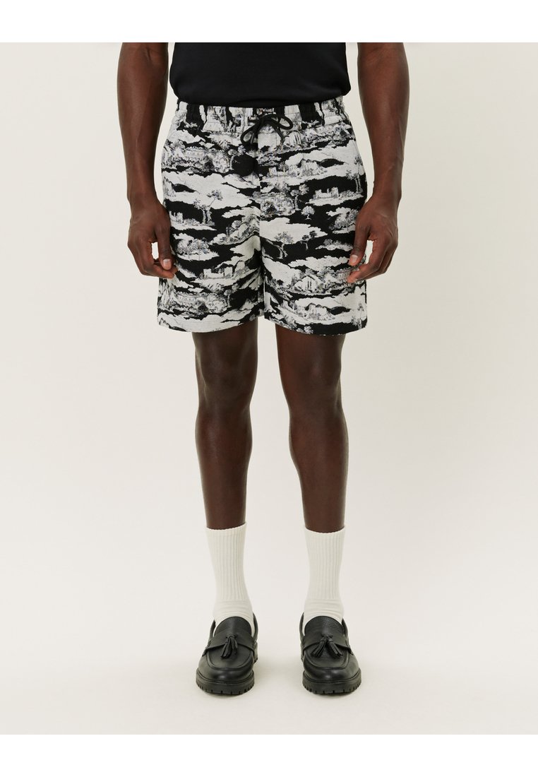 Svart- och vitmönstrade shorts med ett molndesign, som har resårmidja och snöre. Matchas med vita strumpor och svarta loafer.