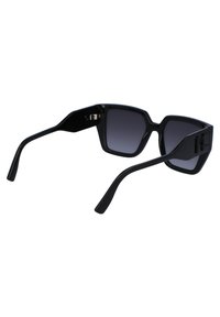 Black sunglasses with a square frame, gradient dark lenses, and sleek arms featuring a logo detail on one side. Smooth plastic material.