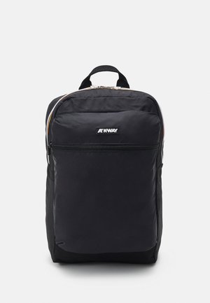 Mochila negra de nailon con una textura suave, que cuenta con un bolsillo frontal con cremallera, un parche con el logo y una asa en la parte superior; diseñada con correas de hombro acolchadas.