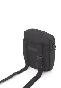 Bolso cruzado de tela negra con parte superior con cremallera, bolsillo frontal y correa ajustable. Presenta el logo de Skechers y un diseño práctico.