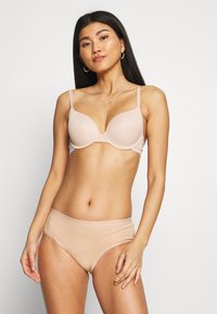 Light beige bra with smooth, molded cups and adjustable straps, paired with matching seamless hipster briefs in a soft, stretchy material.