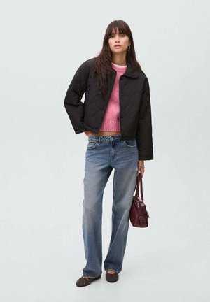 Veste en quilt noir, pull en laine rose, jean bleu décontracté, chaussures plates marron foncé avec clous, et un petit sac à main bordeaux.